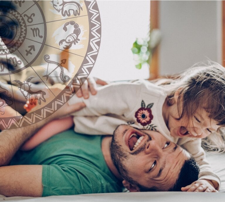 Ein fröhlicher Vater liegt auf dem Rücken und spielt mit seiner lachenden kleinen Tochter, die auf ihm liegt. Über ihnen schwebt eine transparente Scheibe mit verschiedenen astrologischen Symbolen. Sie befinden sich in einem hell erleuchteten Raum, was eine warme und liebevolle Atmosphäre schafft. | © iStock [M]