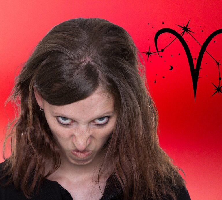 Ein Foto einer Frau mit einem kritischen oder leicht verärgerten Gesichtsausdruck. Sie hat braune Haare, trägt ein schwarzes Oberteil und blickt von unten herauf zur Kamera. Hinter ihr ist ein lebhafter roter Hintergrund mit einem Farbverlauf sowie ein großes schwarzes Symbol für das Sternzeichen Widder, umgeben vom Sternbild Widder. | © Adobe Stock/ tibanna79, Berry Art, Getty Amtes/ jeewan chandra und Artulina via Canvas.com [M]