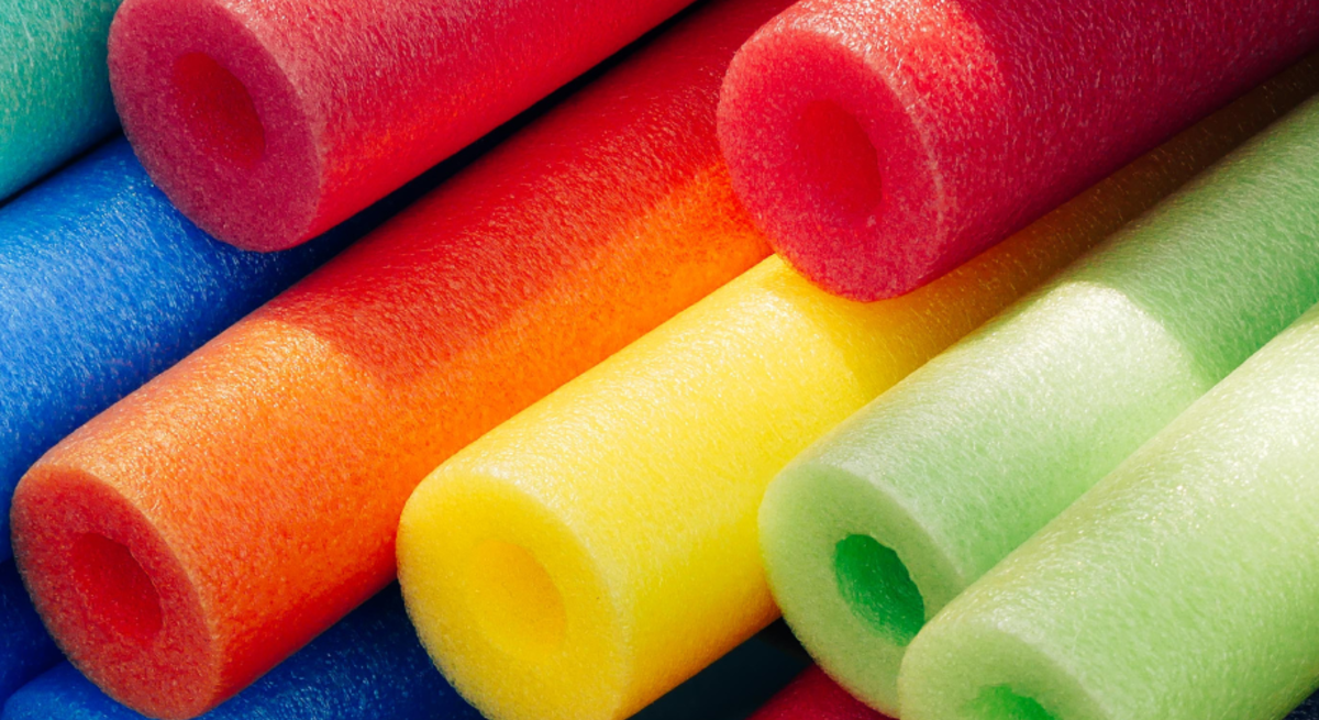 Bunte Schaumstoff-Poolnudeln in Lila, Grün, Gelb und Orange schwimmen, liegen gestapelt oder verschlingen sich auf blauem Untergrund.