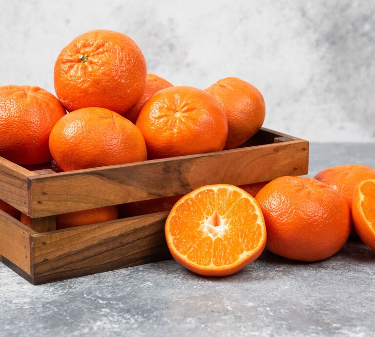 Obstkisten aus Holz mit Orangen gefüllt steht auf einem grauen Untergrund und auch der Hintergrund ist grau. | © Adobe Stock/azerbaijan-stockers
