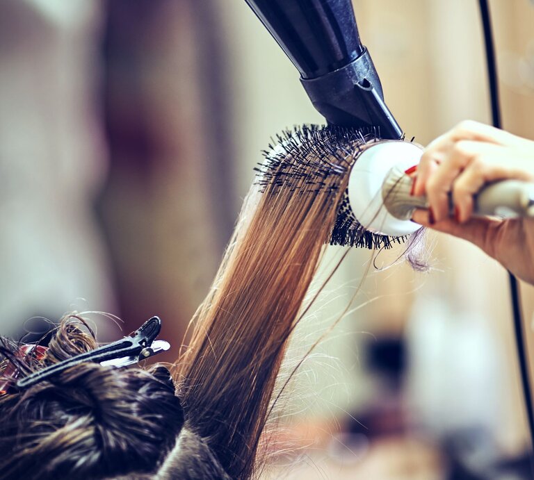 Zu sehen sind Haare, die mithilfe einer Rundbürste in ein Blowout geföhnt werden. | © GettyImages/6okean