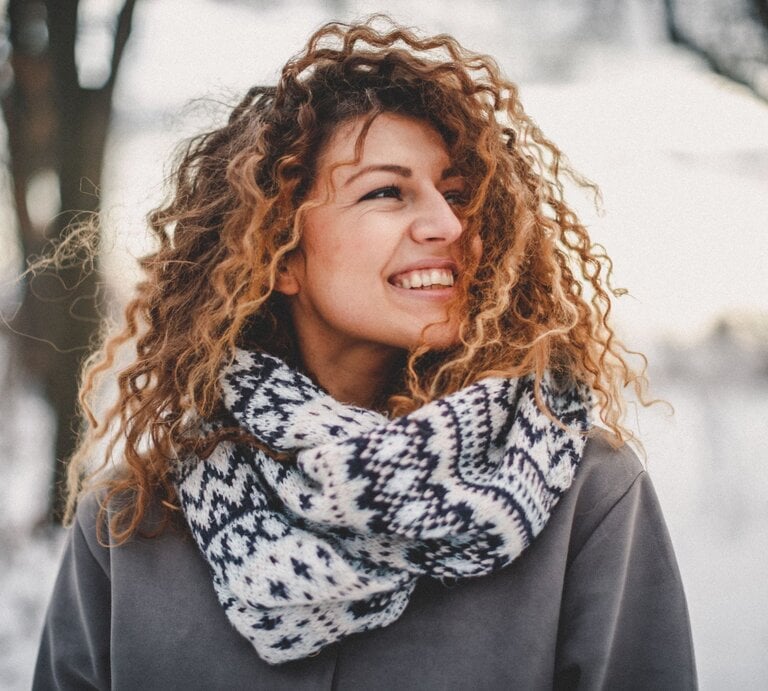 Zu sehen ist eine Frau mittleren Alters, die ihre Locken im Winter offen trägt | © GettyImages/StefaNikolic