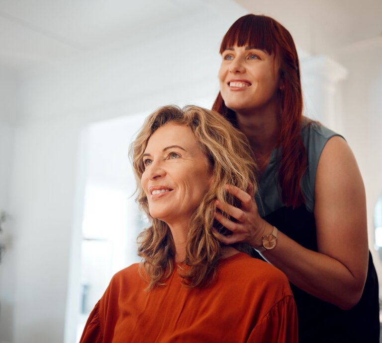 Zu sehen ist eine Frau mittleren Alters, die eine neue Frisur bekommt. | © GettyImages/PeopleImages