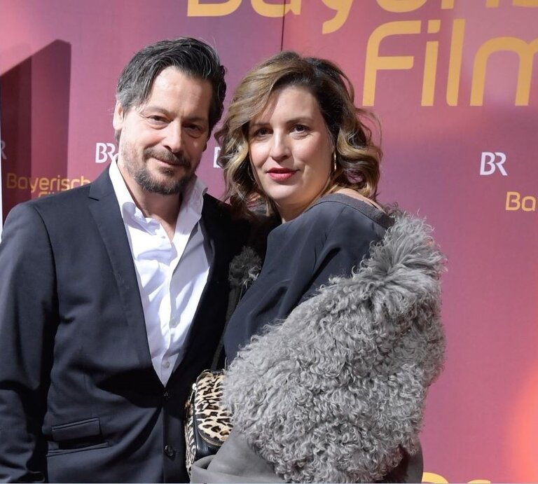 Schauspielerin Elena Uhlig und Schauspieler Fritz Karl stehen bei einer Veranstaltung nebeneinander auf dem roten Teppich | © Marc Mueller/Getty Images