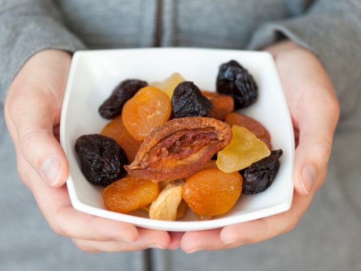 Frau hält Schale mit Trockenobst in der Hand. | © iStock/Professor25