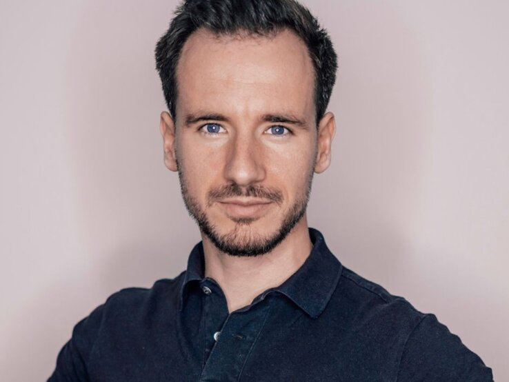 Portrait Sportwissenschaftler Daniel van den Boom: Mann mit kurzen dunklen Haaren und Bart, der in die Kamera blickt und ein dunkles Poloshirt trägt, vor hellem Hintergrund. | © Privatarchiv/ Daniel van den Boom