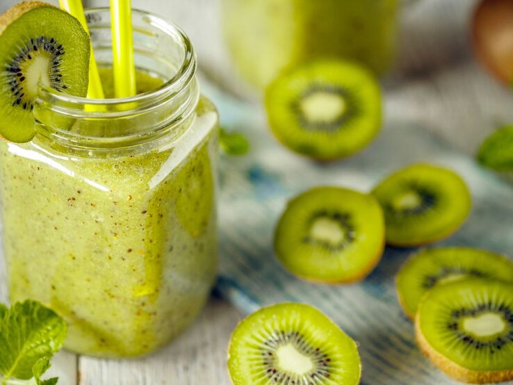 Grüner Kiwismoothie im Glas mit frischen Kiwischeiben – fruchtige Vitamin-C-Bombe, die das Immunsystem stärkt. | © Getty Images Pro/ grafvision via Canva.com