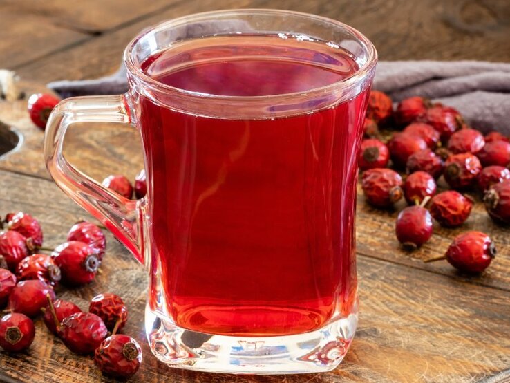 Ein Glas frisch aufgebrühter Hagebuttentee neben getrockneten Hagebutten – reich an natürlichem Vitamin C und ideal zur Stärkung des Immunsystems. | © Getty Images/ Madeleine_Steinbach via Canva.com