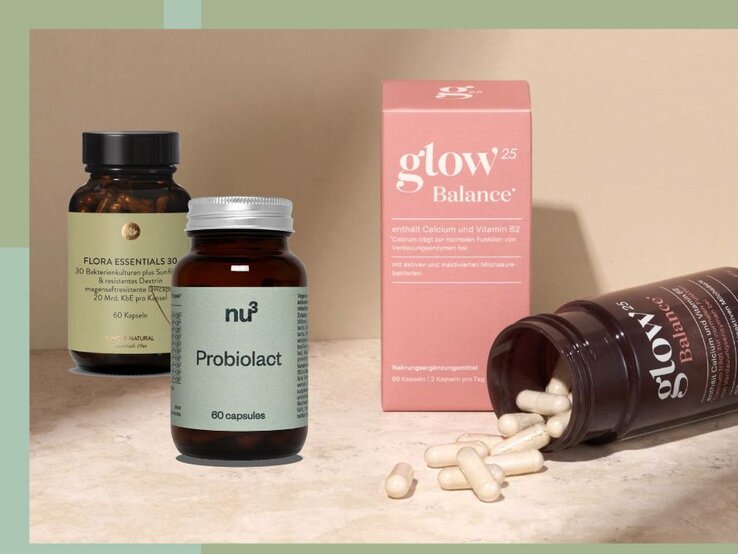 Das Bild zeigt drei Produkte, die Nahrungsergänzungsmittel sind. Links befindet sich ein dunkelbraunes Glas mit grünlichem Etikett, beschriftet mit "FLORA ESSENTIALS 30". In der Mitte steht ein braunes Glas mit silbernem Deckel und der Aufschrift "nu3 Probiolact". Rechts im Bild sind ein rosafarbenes Produktkarton mit der Aufschrift "glow25 Balance" und eine geöffnete dunkle Flasche mit Kapseln zu sehen, die aus der Flasche herausrollen. Der Hintergrund besteht aus einer hellbraunen Fläche und einem grünen Rahmen. | © Glow25, nu3 und Sunday natural
