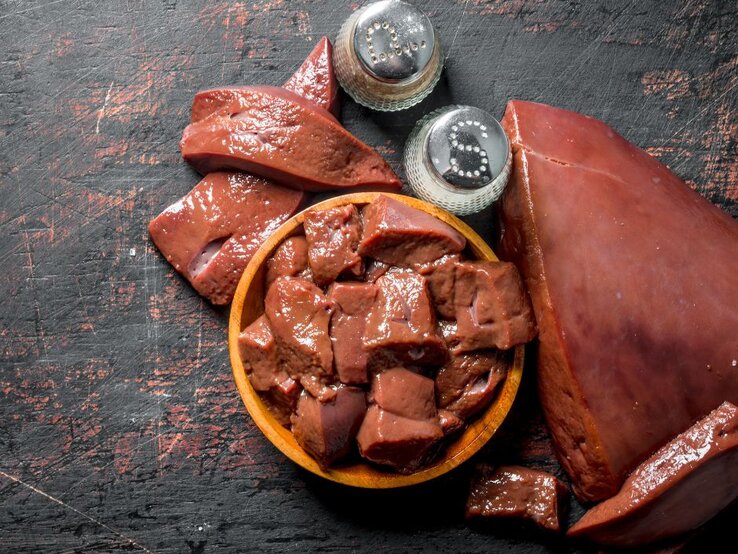 Verschieden geschnittene rohe Leberstücke mit Salz- und Pfefferstreuern. | © ArtemSH via Canva.com