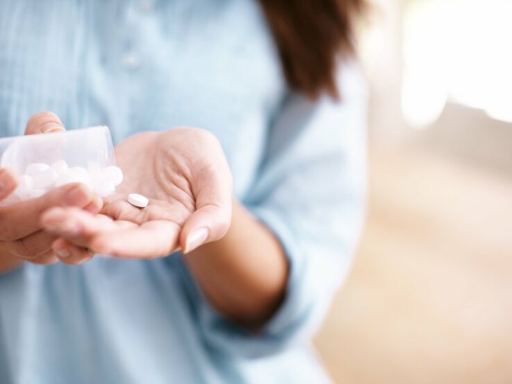 Eine Frau schüttet Tabletten in ihre ausgestreckte Hand
