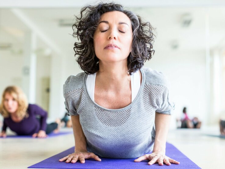 Frau übt in einem Yoga-Studio die Yoga-Übung Kobra aus.