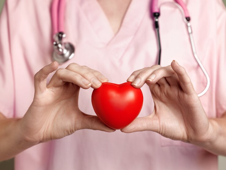 Die Medizin muss weiblicher werden – der #GoRed Day 2025 fordert eine gerechtere Behandlung von Frauen bei Herzkrankheiten. Eine Frau hält ein rotes Herz vor ihre Brust, symbolisch für die Bedeutung der Frauenherzgesundheit.