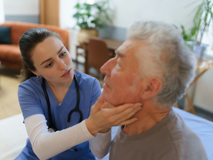 Eine Ärztin untersucht die Lymphknoten eines Patienten.