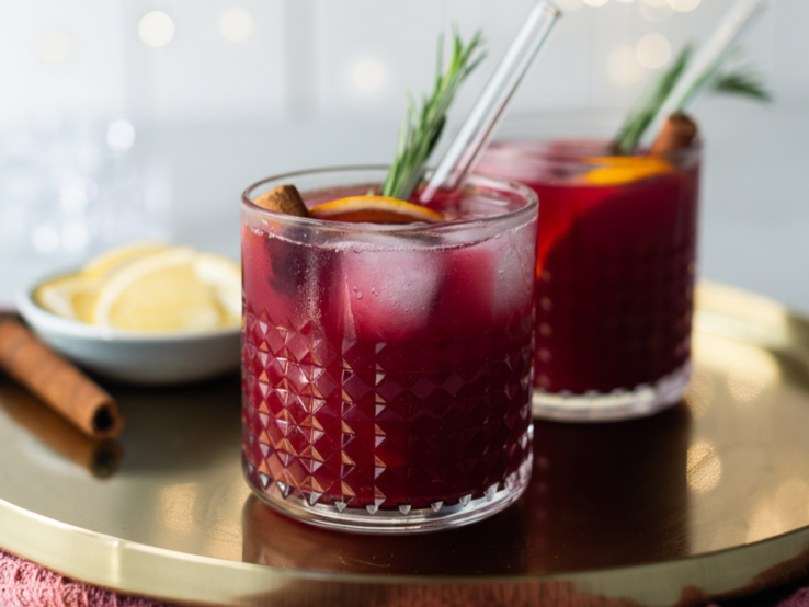 Zu sehen sind zwei Gläser mit rotem Inhalt in einem weihnachtlichen Ambiente