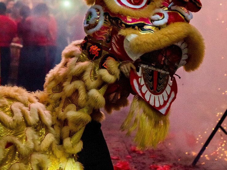 Löwentanz zum chinesischen Neujahrsfest: Ein Mann trägt eine große, bunte Drachenmaske und tanzt durch die Straßen. | © Getty Images/ Nigel Killeen