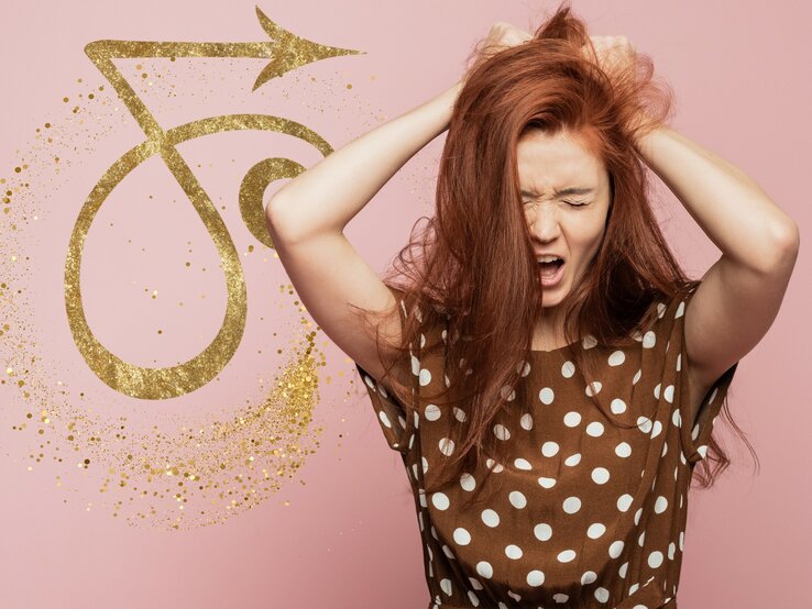 Ein Bild einer Frau mit auffälligem rotem Haar, die sichtlich frustriert und überfordert aussieht, während sie ihre Hände in ihr Haar krallt. Im Hintergrund ist das Symbol für das Sternzeichen Steinbock in Goldglitter zu sehen, welches auf einem rosa Hintergrund hervorsticht. Das Bild vermittelt eine Verbindung zwischen Astrologie und menschlichen Emotionen.