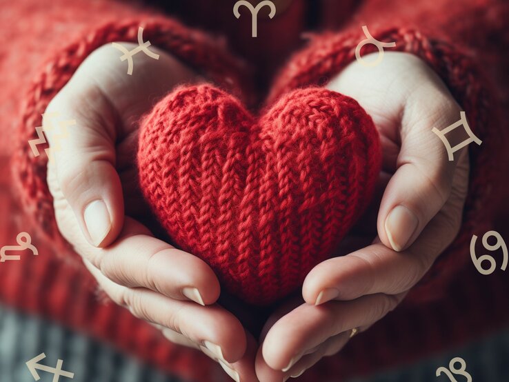 liebe_kw_9.jpg Frauenhände halten ein gestricktes rotes Herz. Darum herum ist der Tierkreis zu sehen mit den astrologischen Symbolen der Sternzeichen.
