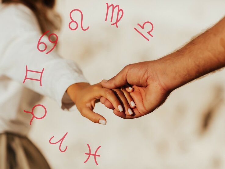Closeup der Hand einer Frau, die ihre in die Hand eines Mannes legt. Umgeben von den astrologischen Zeichen des Tierkreises. 