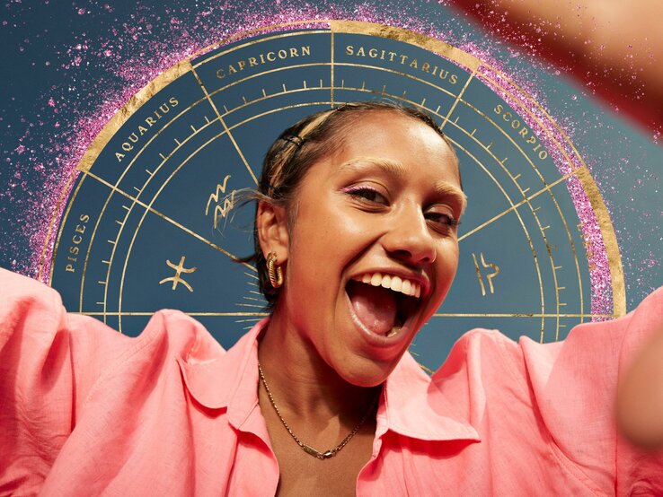 Frau in pink gekleidet die lächelt und von astrologischen Symbolen umgeben ist.