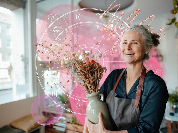 Mitarbeiterin eines Blumenladens die glücklich lächelt und von astrologischen Symbolen umgeben ist.
