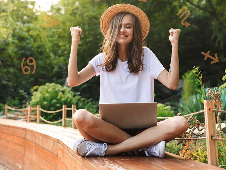 Eine junge Frau sitzt im Schneidersitz draußen in einem Garten mit einem Laptop auf dem Schoß. Sie trägt ein weißes T-Shirt und einen Strohhut und hebt triumphierend die Arme. Um sie herum sind astrologische Symbole von verschiedenen Sternzeichen platziert.