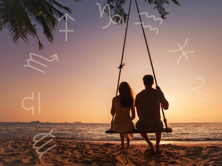 Ein Paar sitzt zusammen auf einer Schaukel am Strand und schaut in den Sonnenuntergang. Der Himmel ist in warmen Orange- und Rosatönen gefärbt. Um das Bild herum sind verschiedene Sternzeichen-Symbole verteilt, die eine astrologische Verbindung andeuten. Eine Palme ragt von oben ins Bild, was die tropische Atmosphäre verstärkt. Die Szene strahlt Ruhe, Romantik und Verbundenheit aus.