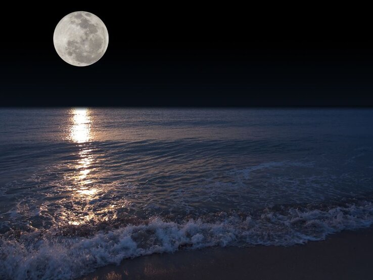 Vollmond über einem Strand bei Nacht.