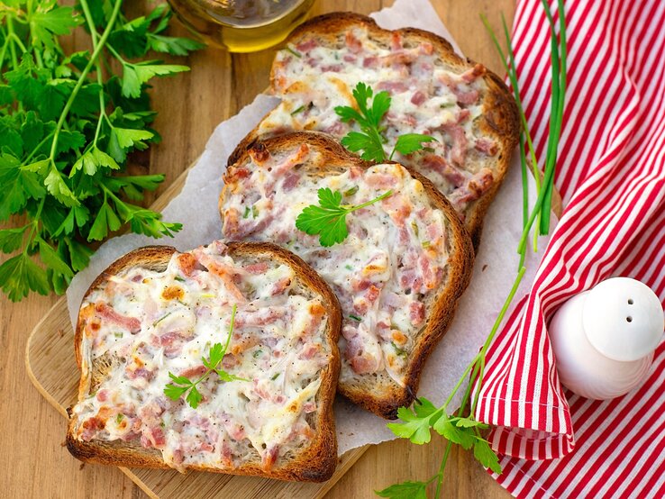 Mehrere Flammkuchen-Toasts auf einem Tisch mit rot-weiß-karierter Tischdecke