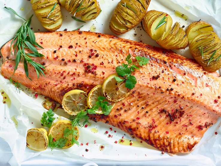 Pulled Lachs gewürzt und mit frischen Kräutern garniert, wird von goldbraun gerösteten Hasselback-Kartoffeln und gegrillten Zitronenscheiben flankiert. 