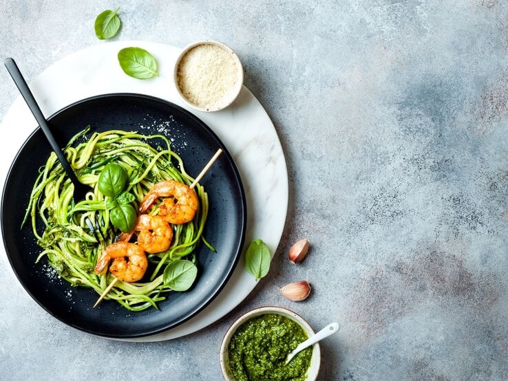 Draufsicht auf Zoodles mit Garnelen auf graublauem Tisch. 