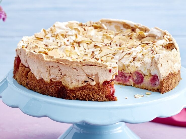 Der Kuchen angeschnitten auf einer Torten-Etagere mit pastelblauem Hintergrund.