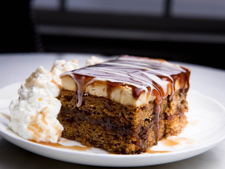 Ein Stück Schmandkuchen mit Karamellsoße und Sahne.