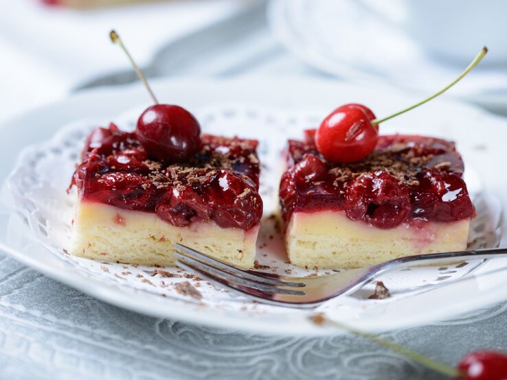 Saftige Kirschtörtchen mit heller Creme und glänzendem Guss, garniert mit frischen Kirschen und geraspelter Schokolade.