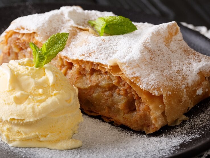 Stück Apfelstrudel auf Teller, daneben Vanilleeis.