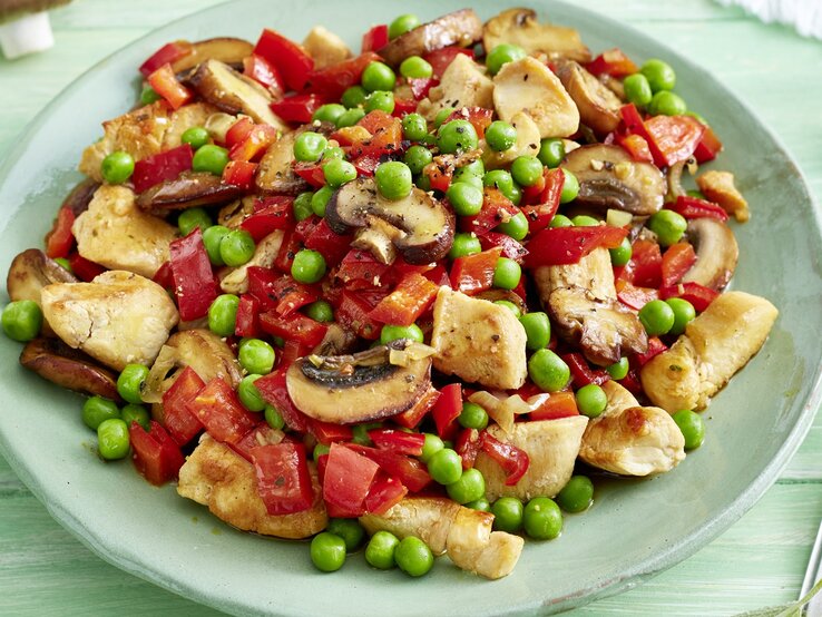 Pilz-Erbsen-Pfanne mit Huhn  /runder Teller / Untergrund Holz 