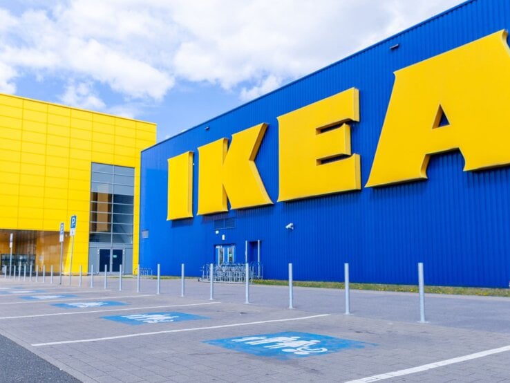 Blick auf ein modernes IKEA-Gebäude mit großer blauer Fassade und gelben Buchstaben an einem sonnigen Tag.