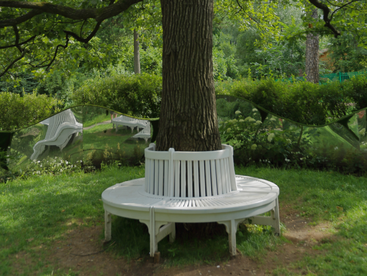 Drei unterschiedliche Baumbänke um Bäume in Parkszenen, jeweils aus Holz oder Stein, umgeben von sattem Grün und Sonne.