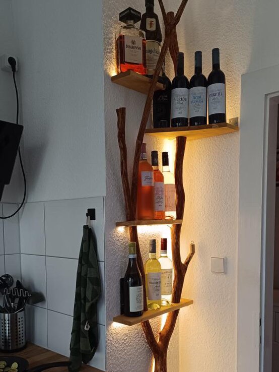 Weinregal Ast | © Leopold Fiedler Stilvolles DIY-Weinregal aus Astholz mit integrierter Beleuchtung, bestückt mit edlen Wein- und Spirituosenflaschen in einer Küche. | © Leopold Fiedler