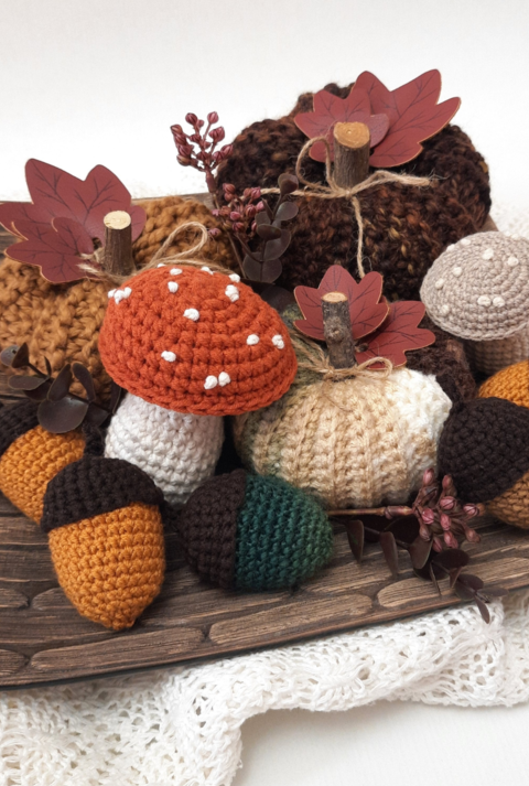 Herbstliche Häkeldeko mit Kürbissen, Eicheln und Pilzen aus Wolle, liebevoll arrangiert auf Holz und Bast mit Lichterkette.