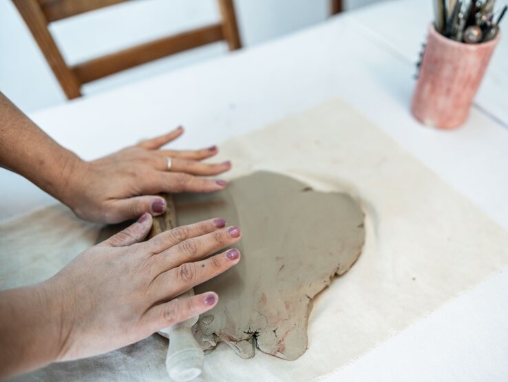 Tonbuchstaben töpfern ist ein supersimpler DIY-Trend Nahaufnahme einer Frau, die in einer Keramikwerkstatt Ton modelliert
