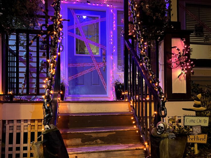 Hauseingang gestalten Halloween  Hauseingang gestalten für Halloween: Mit Lichterketten, Ketten, Skeletten und Spinnennetzen gruselig geschmückter Hauseingang bei Nacht.