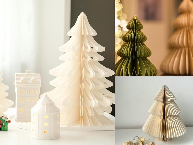 Tannenbaum basteln Faltbare Papierbäume in Weiß, Grün und Beige bilden mit leuchtenden Keramikhäuschen ein stimmungsvolles Winterensemble.