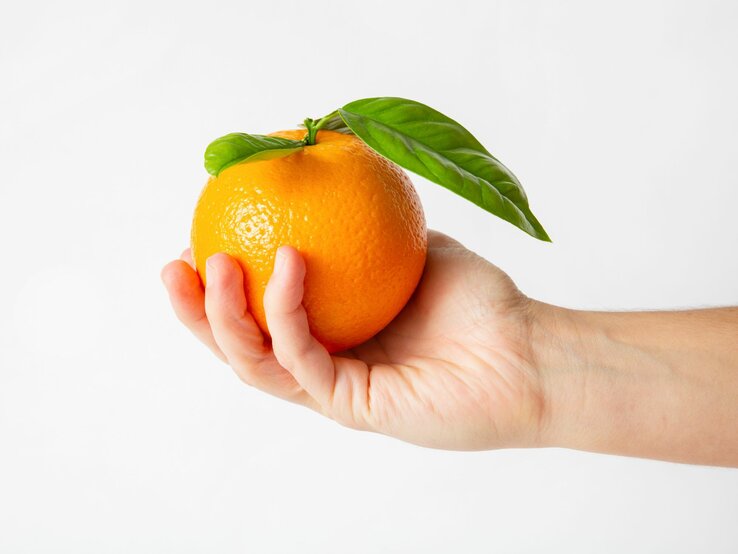 Jemand hält eine Orange in der Hand.