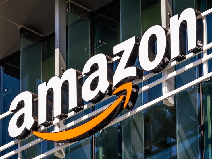 Nahaufnahme des bekannten Amazon-Schriftzugs mit orangem Pfeil auf Gebäudefront.