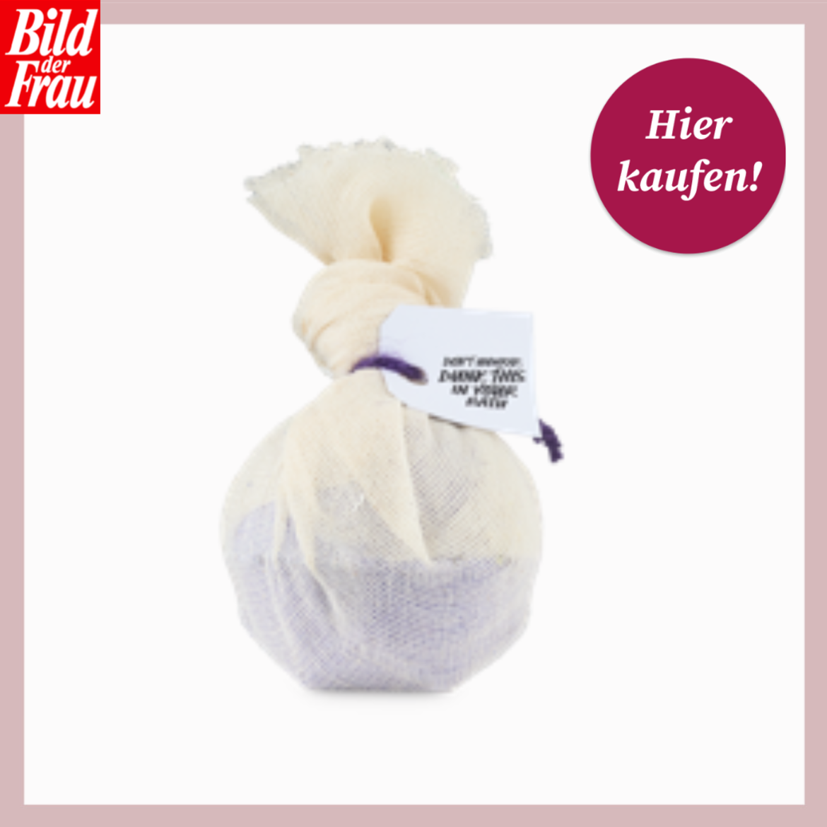 Ein runder Badezusatz in hellem Stoffbeutel mit Etikett und lila Band liegt mittig auf weißem Hintergrund. | © Lush/Canva/Collage:bildderfrau.de