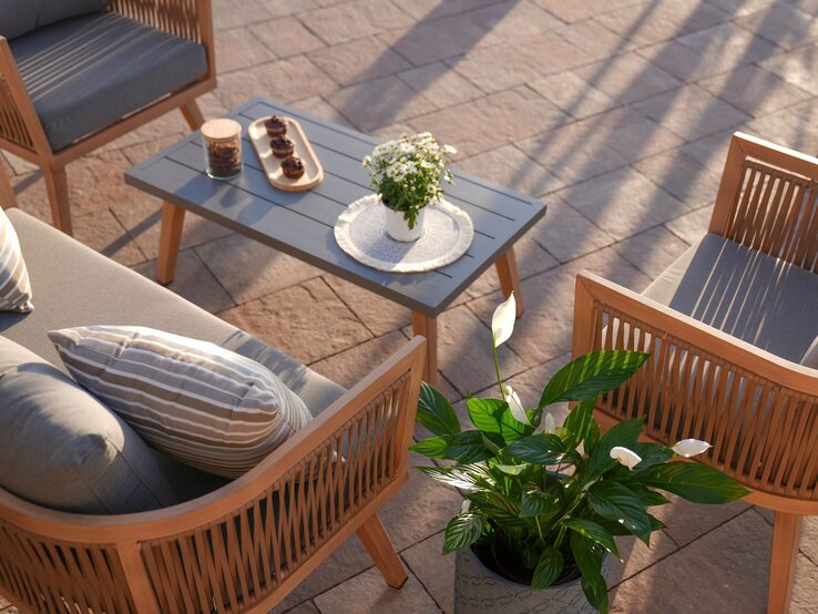 Gartenmöbel kleiner Garten Elegante Gartenlounge mit Holzmöbeln und grauen Polstern um einen Tisch mit Muffins, Blumen und Keksdose in der Abendsonne.