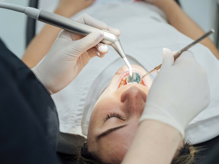 Eine Frau liegt auf dem Zahnarztstuhl und der Zahn wird behandelt.
