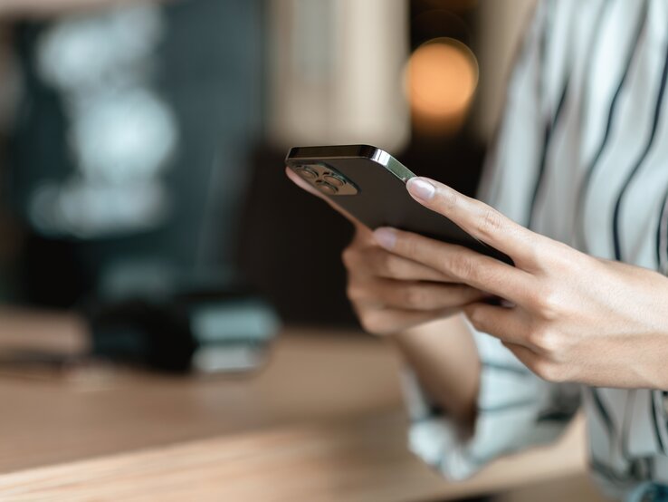 Frau hält ein Handy in der Hand und tippt. 