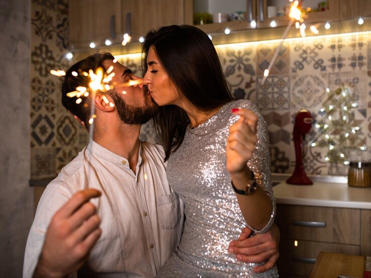 Ein Paar küsst sich und hält dazu angezündete Wunderkerzen in der Hand